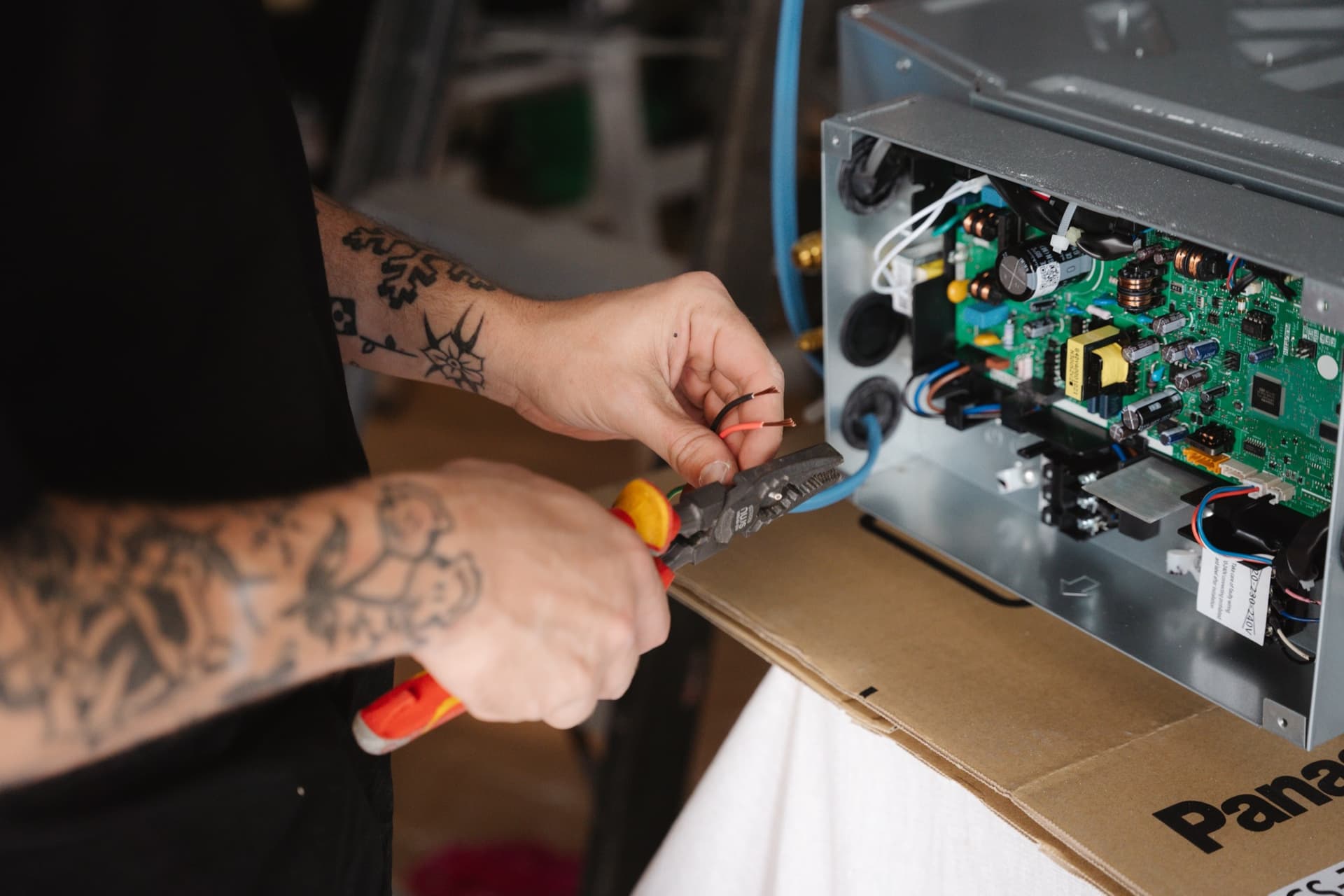 A Virtas technician wiring the control board of a Panasonic ceiling cassette before it goes up