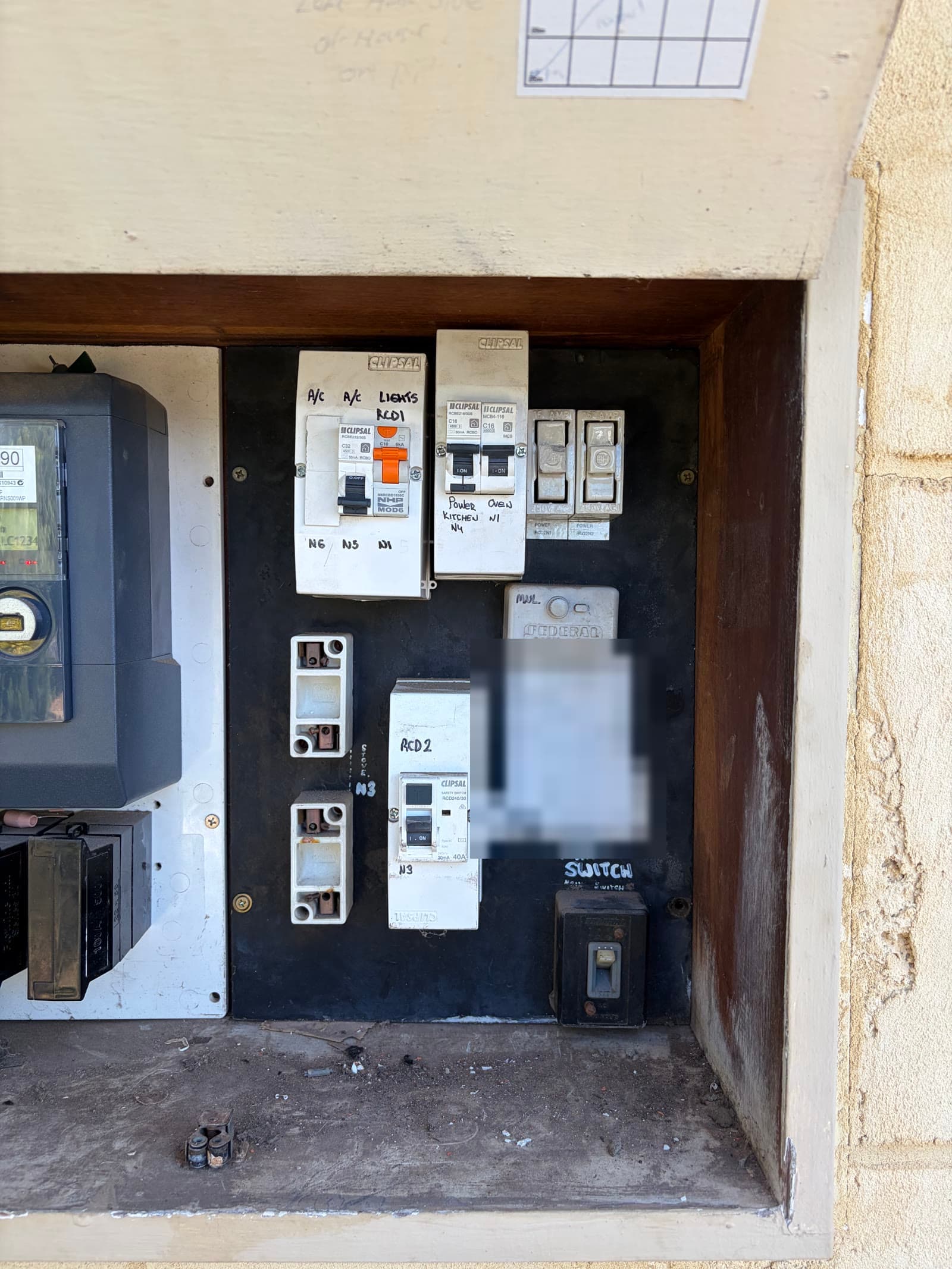An old switchboard with ceramic fuses on an asbestos backing board, before our upgrade